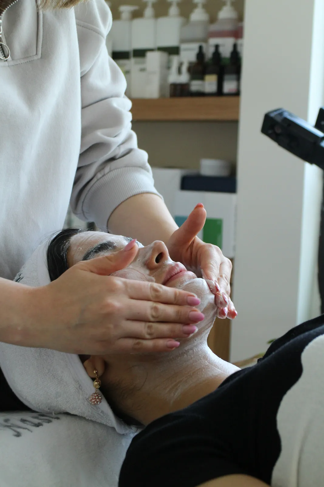 A rolled towel, a bottle of lotion and tulips on a spa table