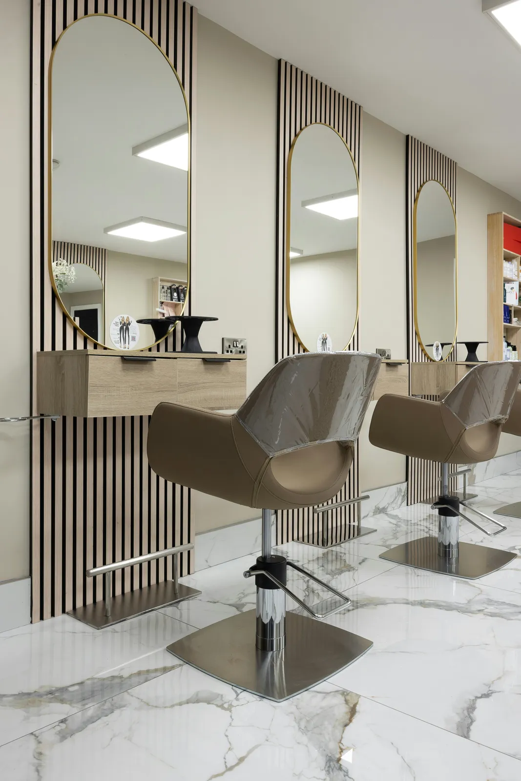 Empty salon chairs in front of a row of mirrors