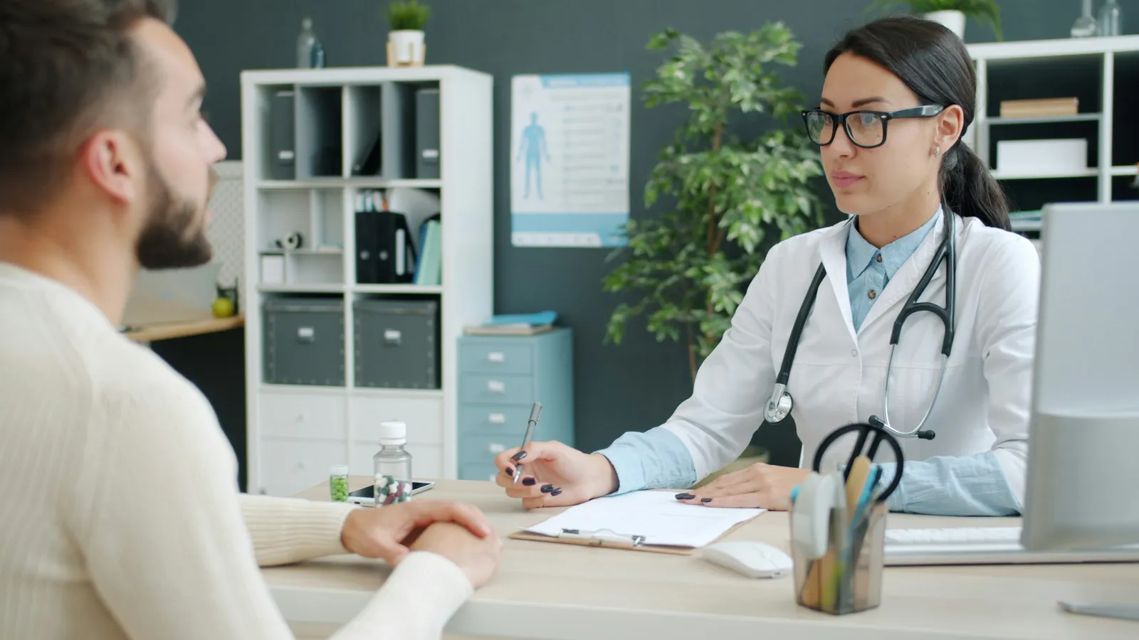 A doctor listening to a patient across the consultation desk