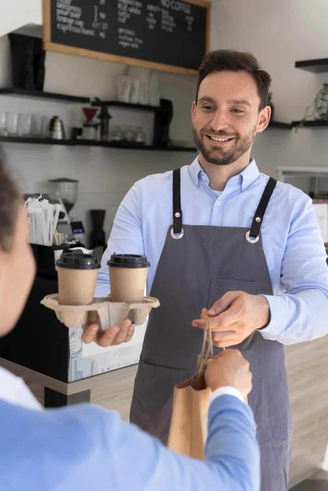 A barista handing a paper bag and coffee across the counter